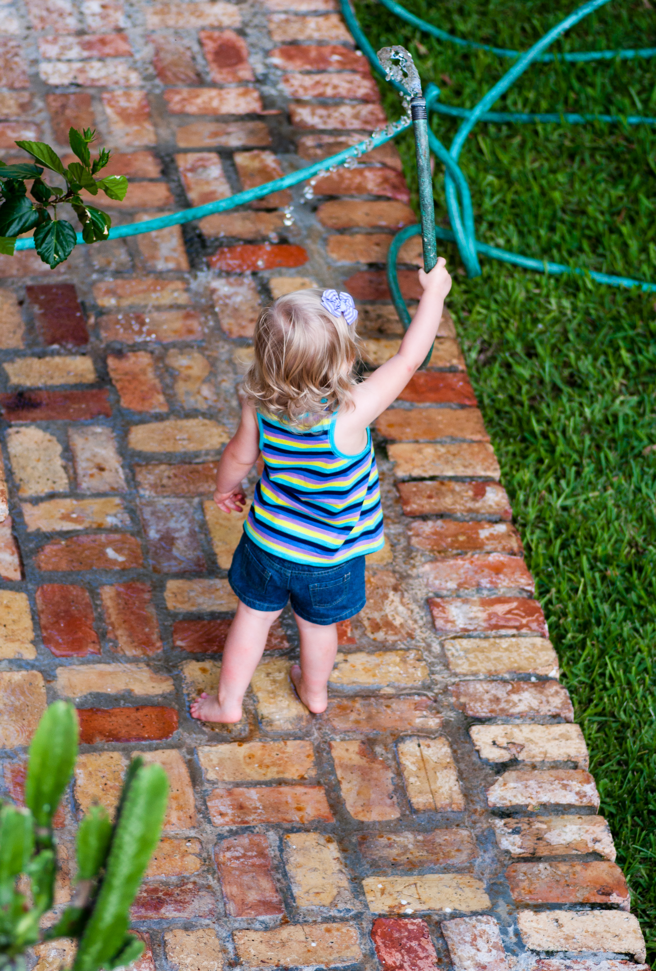 Young Girl playing in the backyard with a water hose