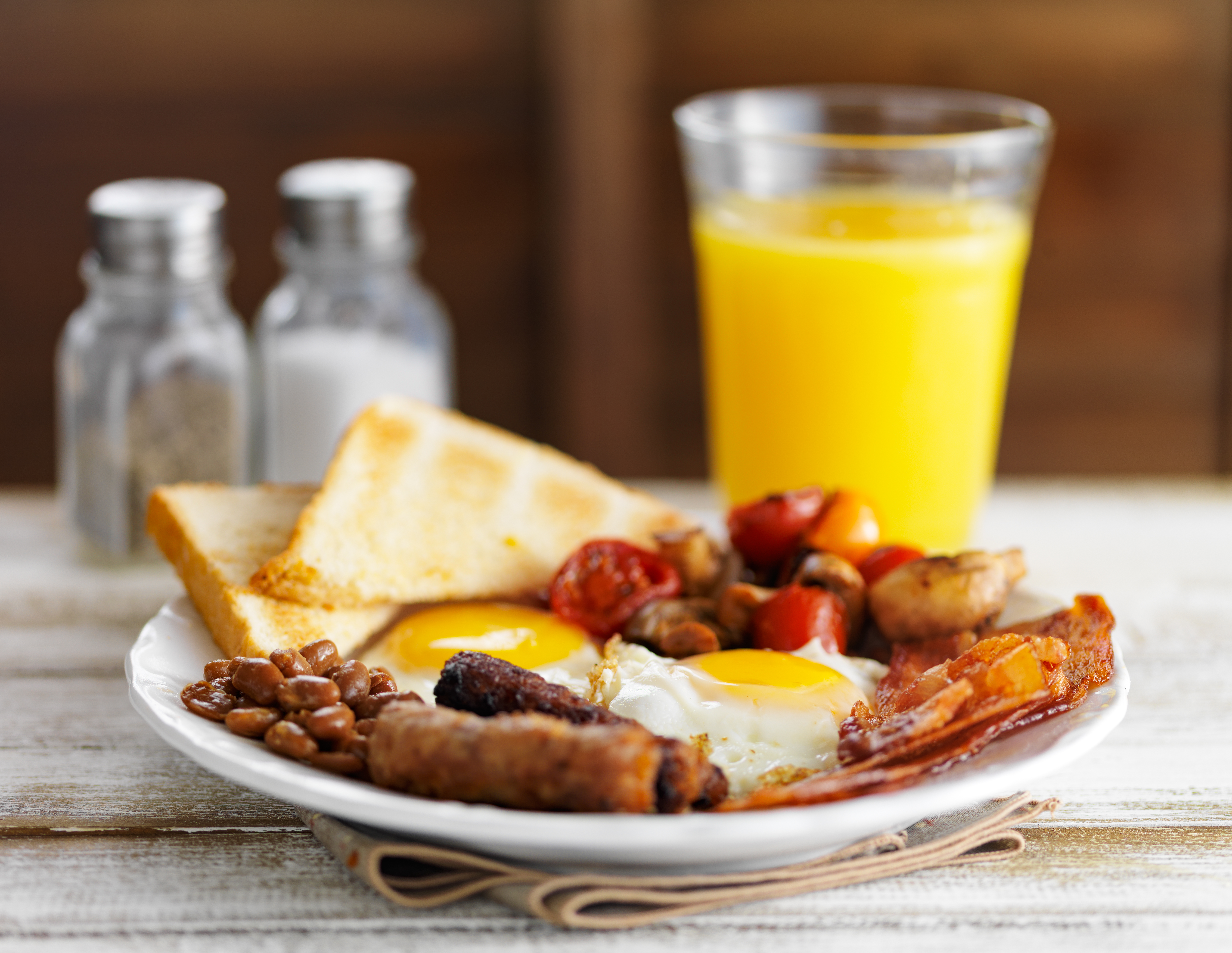 classic english breakfast on rustic table top served with orange juice