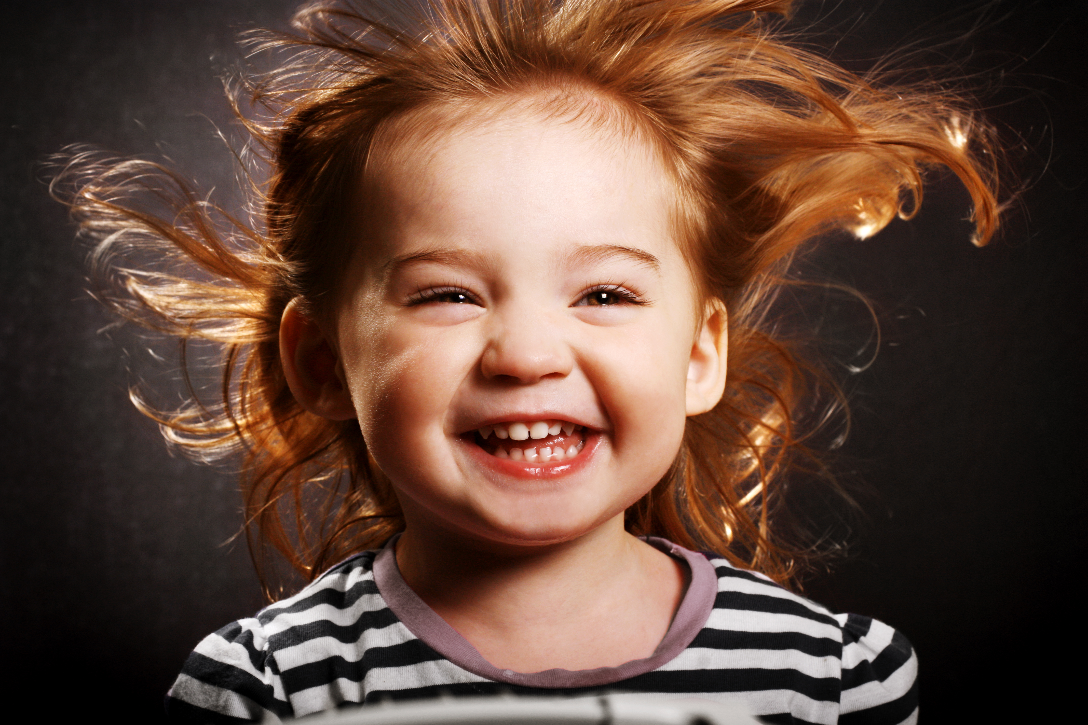 A gorgeous little girl smiling hysterically with the wind in her hair.